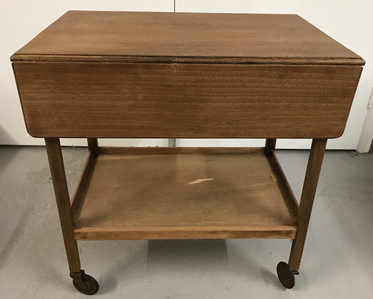 A vintage wooden drop leaf tea trolley with under shelf.