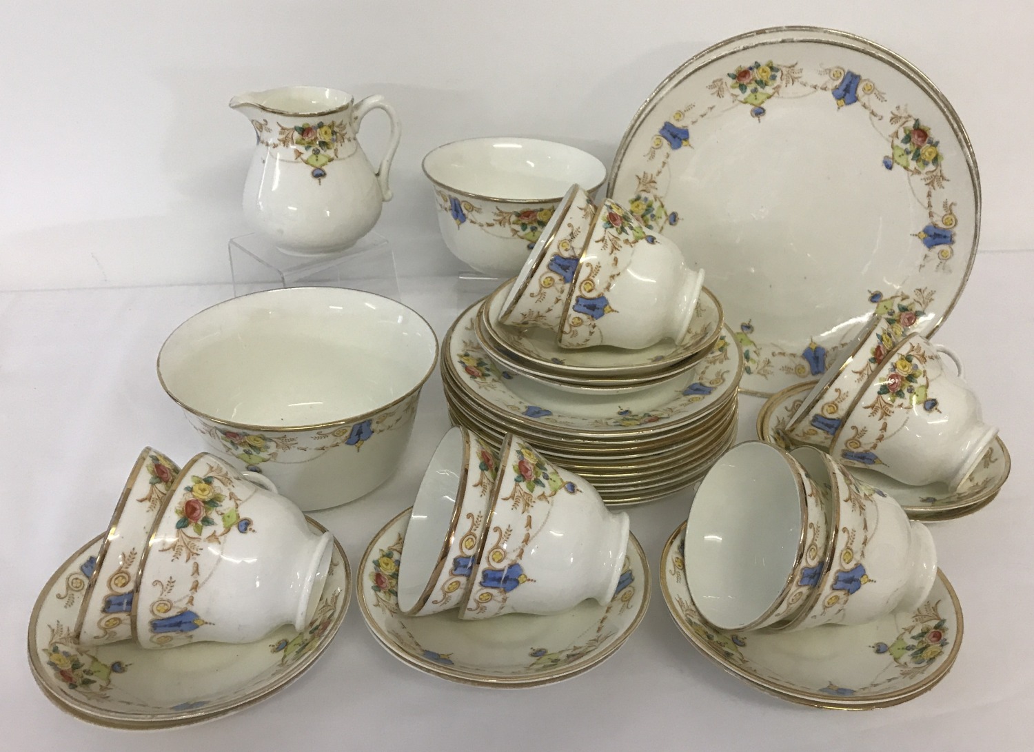 A Victorian ceramic tea set with gilt detail and decorative floral swag design.