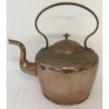 A large antique copper kettle with hooped handle and dovetail joint.