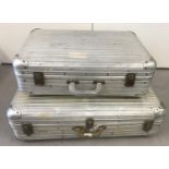 2 vintage aluminium suitcases with plastic handles and lockable catches.