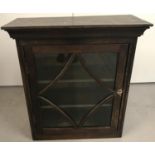 An antique dark oak, glass fronted wall cabinet with decorative carved panel sides.