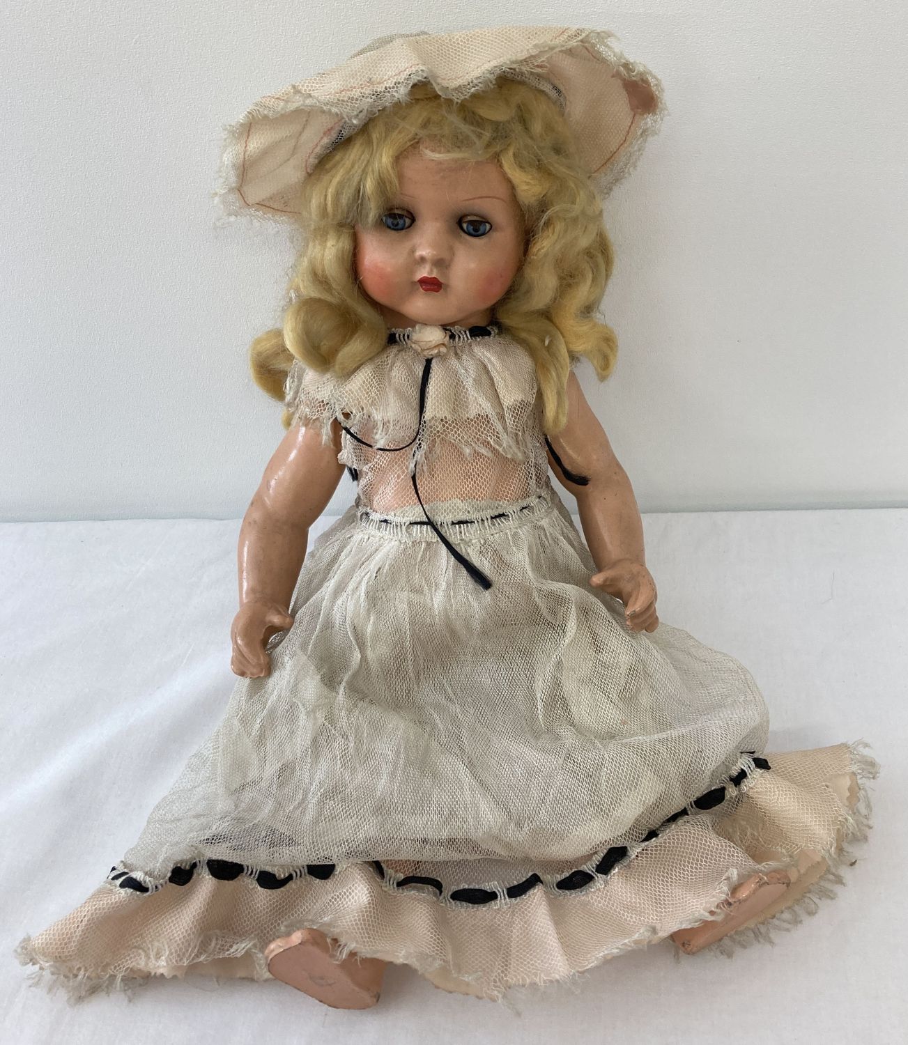 A vintage composite doll with closing eyes, painted lips blonde hair and cryer box.