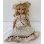 A vintage composite doll with closing eyes, painted lips blonde hair and cryer box.