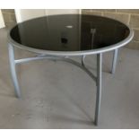 A modern metal framed, glass topped, circular garden table.