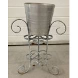 A garden wine cooler. Aluminium wine cooler bucket on a wrought iron scroll detail stand.