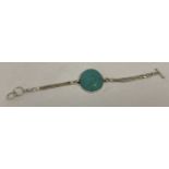 A white metal and turquoise bracelet.