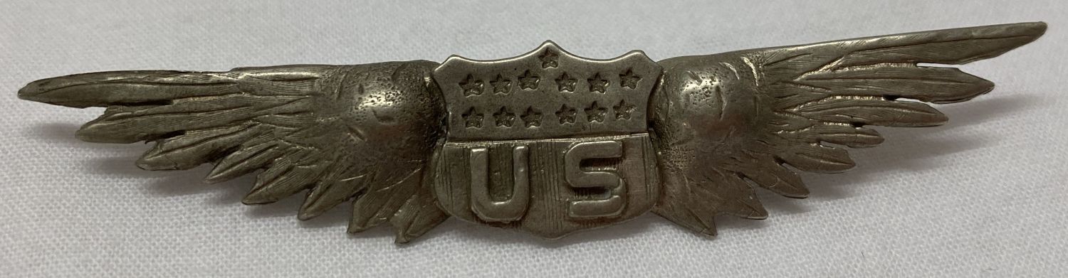 A WWI style silver US pilots wings badge. 'Made in Paris' impressed to reverse.