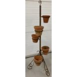 A wrought iron garden plant pot stand with scroll work feet and decoration to top.