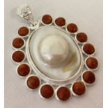 A large oval shaped coral and pearl pendant with pierced work bale.