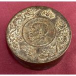 A circular bronze scroll weight with dragon detail to top rim.