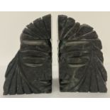 A pair of carved black slate book ends portraying faces.