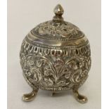 A Persian silver 3 footed pepperette of spherical form, with ornate floral decoration throughout.