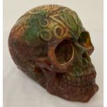A large carved multi coloured resin, amber style skull figurine decorated with Pagan style symbols.