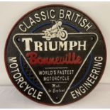 A circular painted cast iron "Triumph Bonneville" wall hanging plaque.