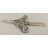 A white metal, pearl handled babies rattle with nursery rhyme detail.