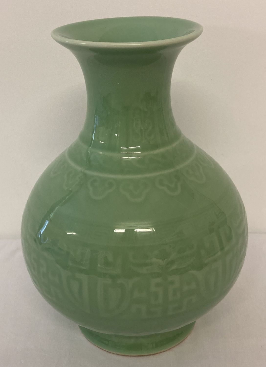 A green glazed Chinese ceramic vase of bulbous form with wide lipped neck.