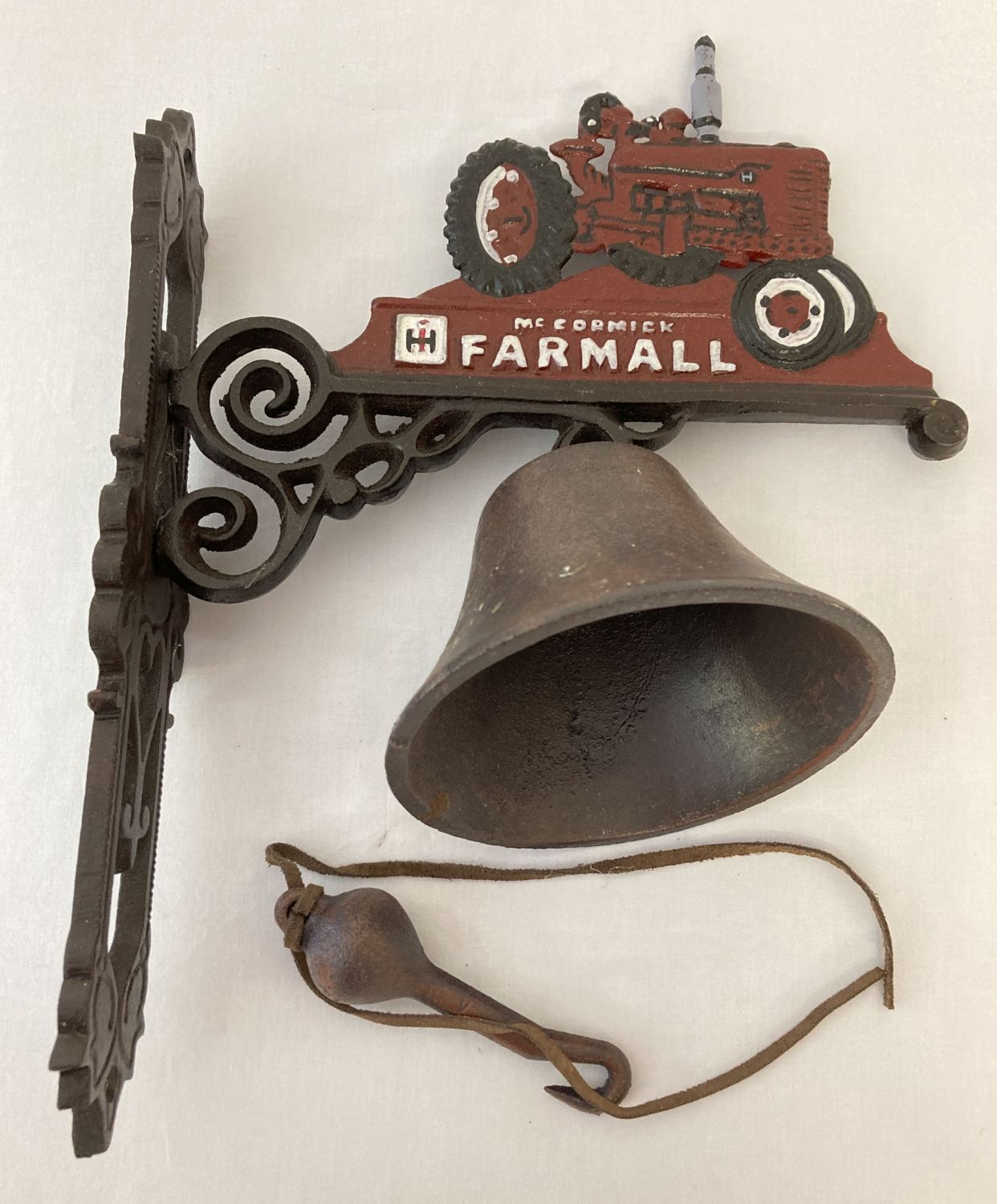 A painted cast iron wall hanging bell with "McCormick Farmall" logo and tractor.