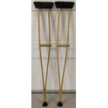 A pair of wooden crutches with rubber feet and padded under arm supports.