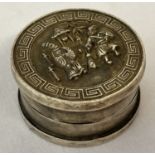 A Chinese white metal rouge pot with figural detail to lid and Greek key design to rim.