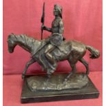 A large bronze figure in the form of a Native American riding a horse.