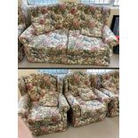 A metal framed 2 seater sofa and matching arm chairs in a floral design upholstery.