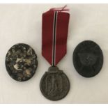 A WWII style German Eastern Front medal and ribbon, together with 2 pin back wound badges.