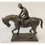 A large bronzed cast metal figurine of a horse and jockey.