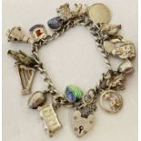 A vintage silver charm bracelet with 17 silver and white metal charms, complete with safety chain.