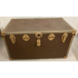 A large travelling trunk with metal banding, corner guards and leather carry handles.