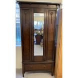 A vintage dark wood single wardrobe with mirrored door, carved appliques and plinth top.