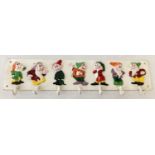 A cast metal wall hanging coat hook with painted seven dwarves detail.