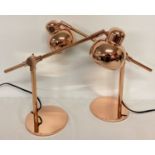 A pair of new copper angle poise style desk lamp.
