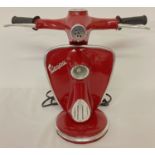 A novelty table lamp in the shape of the handlebars of a Vespa scooter, in dark red.