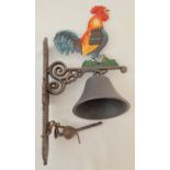 A painted cast metal wall hanging garden bell with cockerel detail.