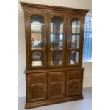A large mirror backed, solid wood display unit with glass doors and cupboard base.