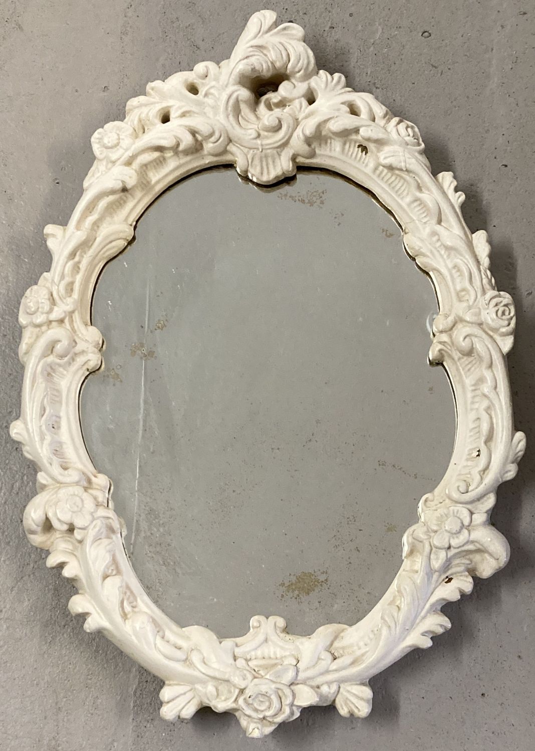 A wall hanging white painted decorative moulded framed oval mirror.