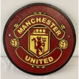 A painted cast metal circular shaped Manchester United Football club wall hanging plaque.