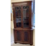 A large reproduction mahogany corner unit with glass doors and interior shelves to top.