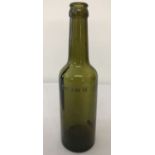 A WWII style German green glass beer bottle with engraved detail.