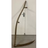 A large vintage wooden handled scythe.