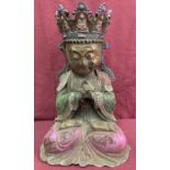 A hollow bronze figure of a seated Oriental Deity with painted detail.