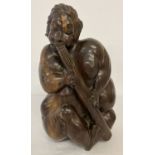 A heavy hardwood carved figure of a tribesman playing a pipe.