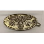 A reproduction Gestapo warrant tag. Oval shaped silver coloured metal with eagle to front.