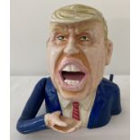 A painted cast metal novelty money bank in the form of Donald Trump.