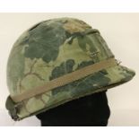 A Vietnam War era US M1 helmet with reversible "Mitch" camo cover and original Vietnam War era liner