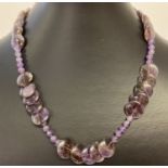 A 17" amethyst beaded necklace with circular and spherical shaped beads & a white metal T bar clasp.