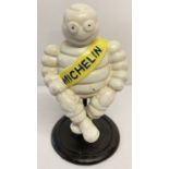 A painted cast iron advertising Michelin man seated figurine on pedestal base.