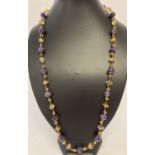 A 27" beaded necklace with amethyst, peridot, citrine and garnet beads & gold tone hook clasp.