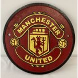 A painted cast metal circular shaped Manchester United Football club wall hanging plaque.