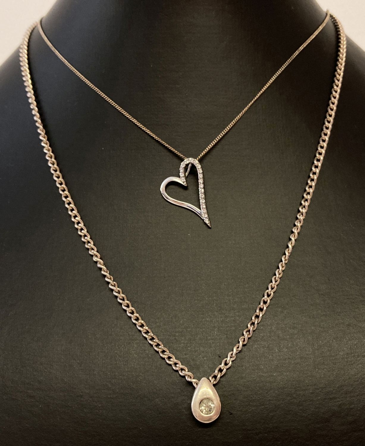 2 modern design silver necklaces. A curb chain with teardrop pendant set with a clear stone.